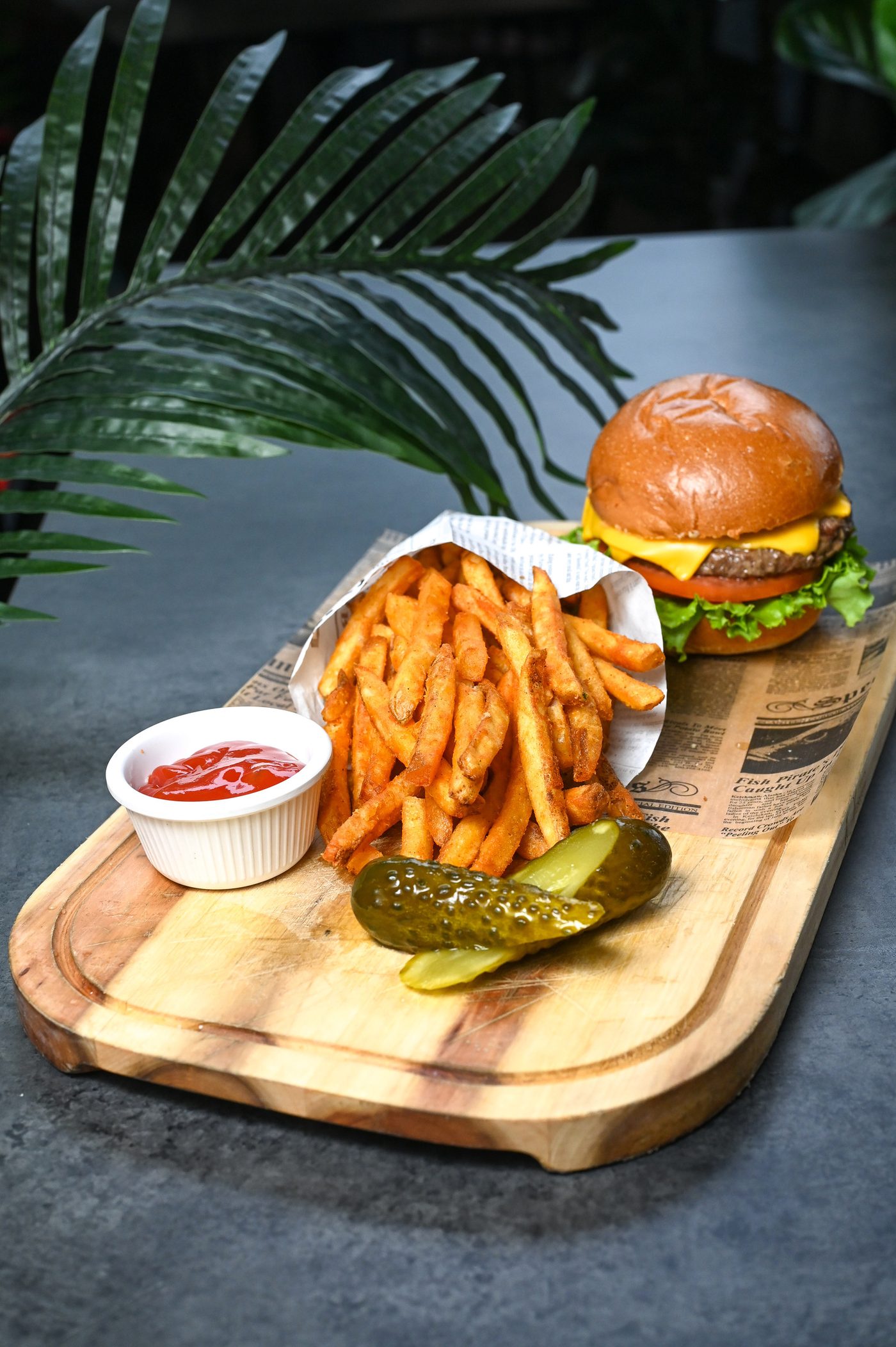 Cheeseburger and curly fries on a board